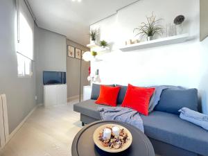 sala de estar con sofá azul y almohadas rojas en Formidable Alonso cano en Madrid