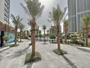 a row of palm trees in a courtyard with buildings at Sunset at Creek Beach - Vacationer in Dubai