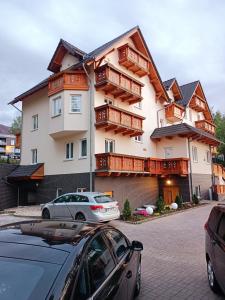 ein großes Haus mit Holzbalkonen und einem Auto vor dem Haus in der Unterkunft Studio TERJANO in Karpacz