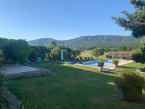 a garden with a swimming pool and mountains in the background at Le Hameau des vanades in Ampus