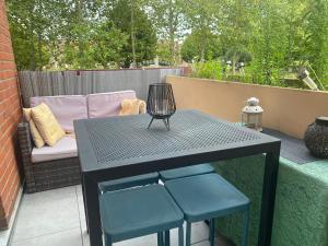 - une table noire et 2 chaises bleues sur la terrasse dans l'établissement Cosy room chez l'habitant, à Montigny-le-Bretonneux