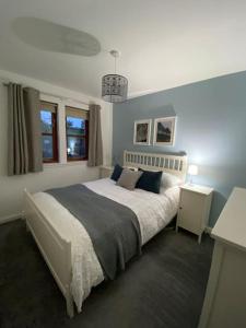 ein Schlafzimmer mit einem großen weißen Bett mit blauen Wänden in der Unterkunft Lanfine View 1 at Loudoun Mains with Hot Tub in Newmilns