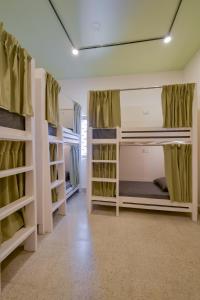 a room with two bunk beds with green curtains at Snore Summore, Hostel in Koramangala in Bangalore