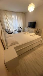 a bedroom with a large bed with two chairs and a tv at Soflu apartments Plovdiv in Plovdiv