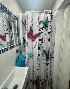 uma casa de banho com uma cortina de chuveiro com borboletas em La casita de los sueños em Casarrubios del Monte