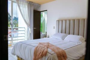 ein Schlafzimmer mit einem großen Bett und einem großen Fenster in der Unterkunft Apartamento a unas cuadras de Condado Concepción Carretera a El Salvador in Guatemala