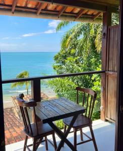 a table and chairs on a balcony with a view of the ocean at Pousada Aroeira Eco in Morro de São Paulo