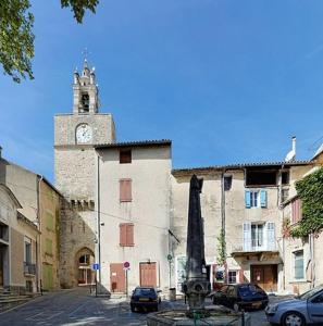 um edifício com uma torre de relógio numa rua em Charmante maison de village au coeur du Luberon em Cucuron
