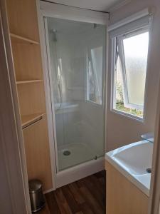 La salle de bains est pourvue d'une douche, d'un lavabo et d'une fenêtre. dans l'établissement Mobil-home grau du roi vagues Océanes, au Grau-du-Roi