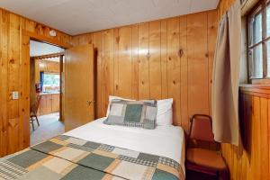een slaapkamer met een bed in een kamer met houten wanden bij Ritter Cottage - Cabin #4 in Saint Germain