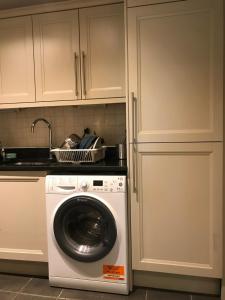 a washing machine in a kitchen with white cabinets at Key & Flowers - Kensington Residence 1 in London