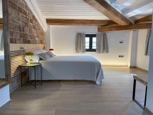 una camera con un letto bianco e un muro di mattoni di ROS CENTRIC Cal Ros a Montblanc