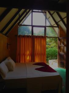 uma cama num quarto com uma grande janela em Rainforest cabin em Deniyaya