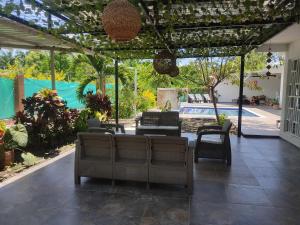 eine Terrasse mit Sofas und Stühlen sowie einem Pool in der Unterkunft Casa Hotel el Encanto de Carmen 