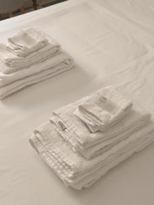 dos pilas de toallas blancas sentadas en una cama en room private bathroom in shared apartment 50m from Gibraltar en La Línea de la Concepción