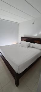uma cama grande num quarto branco com em CASA LUXURY em Villavicencio