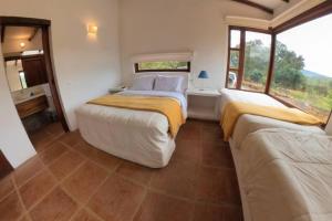a bedroom with two beds and a large window at Casa La Picaza in Villa de Leyva