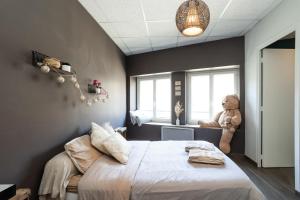 una camera da letto con un grande letto con un orsacchiotto alla finestra di Charmant logement Villefranche a Villefranche-sur-Saône