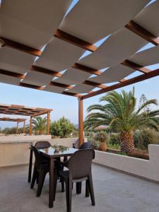 eine Terrasse mit einem Tisch, Stühlen und einer Palme in der Unterkunft Olivar Suites in Palekastro