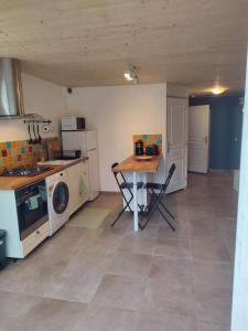 een keuken met een tafel, een wasmachine en een droger bij Logement avec terrasse Millau in Millau