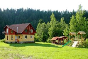 uma casa com um parque infantil num campo com árvores em Kristóf kulcsosház em Gheorgheni