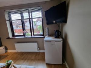 a room with a refrigerator and a flat screen tv at Private room City skyline and mountain views close too belfast centre and airports free parking in Belfast