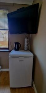 a flat screen tv on top of a small refrigerator at Private room City skyline and mountain views close too belfast centre and airports free parking in Belfast