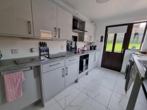 a kitchen with white cabinets and a large window at Private room City skyline and mountain views close too belfast centre and airports free parking in Belfast