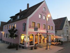 ein großes rosafarbenes Gebäude mit einem Hotel in einer Straße in der Unterkunft Hotel Weisses Lamm in Allersberg