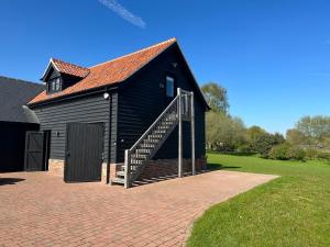 Newbourn的住宿－The Old Piggery, Cart Lodge in Newbourne，前面有楼梯的黑色谷仓