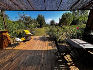 eine Holzterrasse mit einem Tisch und Stühlen darauf in der Unterkunft Chalet Ecolodge Mazion in Mazion