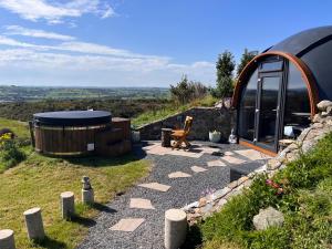 Un jardín con jacuzzi y un edificio. en Hilltop Hideaway - Secluded pod with private hot tub, en Newry