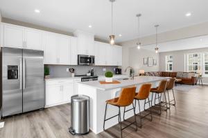 a kitchen with white cabinets and a kitchen island with bar stools at Stunning and Spacious 4-bedroom Townhome! The Dye at Barefoot Resort 403 in North Myrtle Beach