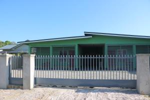 a green building with a fence in front of it at Schitterend gelegen tweekamerwoning in Paramaribo