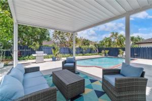 a patio with chairs and a swimming pool with a white pergola at Kendall Vacation Luxury Home in Miami