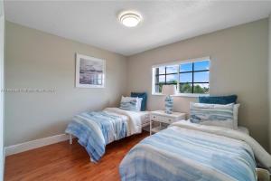 1 dormitorio con 2 camas y ventana en Kendall Vacation Luxury Home, en Miami