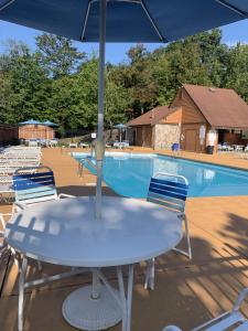 a table and chairs with an umbrella in front of a pool at 7 Springs Ski & Mountain Adventure Condo condo in Champion