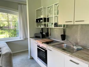 a kitchen with white cabinets and a sink and a window at Ferienwohnung FÜNF Hof Himmelgrün in Saal +28 photos