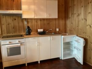 cocina con armarios blancos y nevera abierta en Espes residens en Jordal
