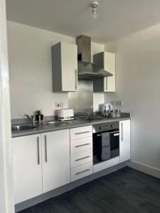 cocina con armarios blancos y fogones en Entire Apartment in Greater Manchester en Mánchester