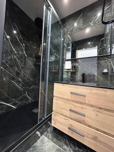 La salle de bains est pourvue d'une douche en verre et d'un lavabo. dans l'établissement Appartement Jacuzzi, à Narbonne