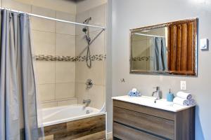 a bathroom with a tub and a sink and a mirror at Nelson Warm Log Cabin with Private Hot Tub in Rivière-Rouge