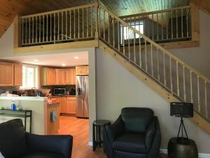a living room with two chairs and a staircase at Hidden Lakefront Retreat in Sherburne