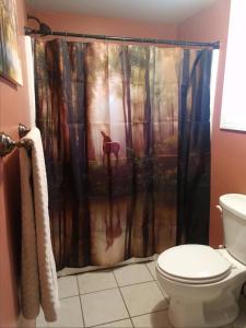 a bathroom with a shower curtain with a deer in the woods at Hidden Lakefront Retreat in Sherburne