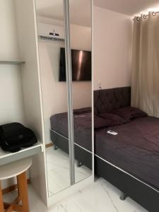 Dormitorio pequeño con cama y espejo en Studio - frente a praia, en Salvador