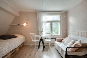 een slaapkamer met een bed, een tafel en een bank bij Cosy home & terrace in a 1910-wooden house in Turku