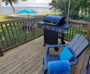 a grill and a chair on a deck with a table at Stunning Modern Container Home on Golden Lake in Killaloe Station