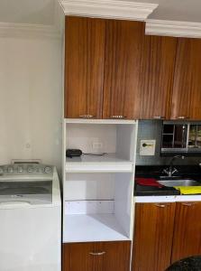 una pequeña cocina con armarios de madera y estanterías blancas en apartamento poblado, en Medellín