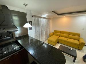sala de estar con sofá amarillo y cocina en apartamento poblado, en Medellín