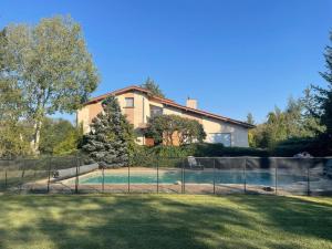 a house with a fence around a swimming pool at Villa d'architecte 200m² avec piscine privée et cheminée - FR-1-496-35 in Pommiers-en-Forez